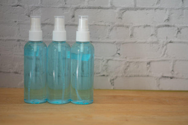 木桌上放了三小瓶酒精喷雾。清洁喷雾，对抗冠状病毒、covid-19和细菌。洗手液装在泵瓶里。图片下载