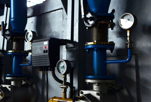 自动工业燃烧器控制单元。用于测量压力的圆形机械压力表。锅炉房加热管道附近有保温涂层的仪表。油气管道图片下载