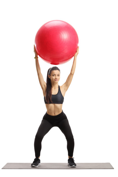 年轻女子在运动服装与红色健身球在垫子上锻炼图片下载