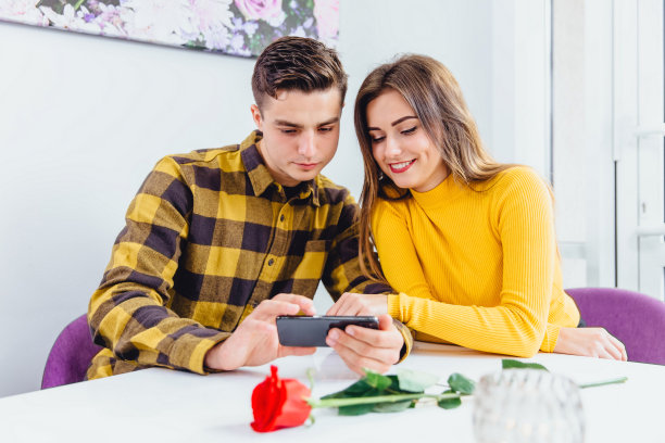 夫妇选择一些产品，用智能手机在网上购买。男孩和女孩穿着黄色的衣服。图片下载