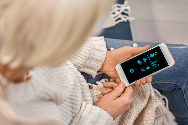 老年妇女使用带有智能家居应用程序的现代智能手机，在家休息图片下载