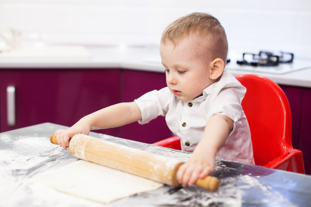 小男孩在准备面团。男孩在厨房揉面。图片下载