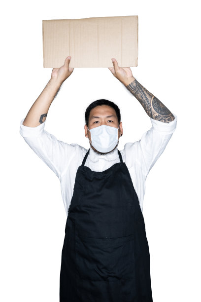 留着胡子的亚洲男侍者、身穿黑色围裙带着医用口罩的厨师正拿着纸板在白色背景下工作。抗议、注意、要求的概念。放置文本或复制空间。剪切路径。图片下载