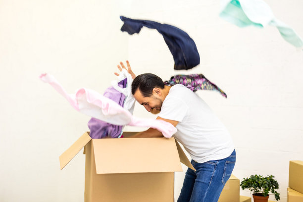 一个男人看起来很疯狂，打开纸板箱，扔掉他的东西，把新公寓弄得一团糟。图片下载