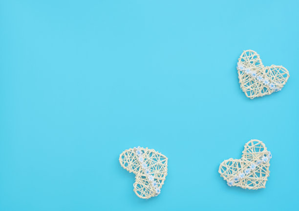 白色藤心与丝带与花在蓝色的背景。母亲节，情人节，婚礼，生日或其他合适的事件庆祝贺卡的概念。平铺与复制空间的文本。图片下载