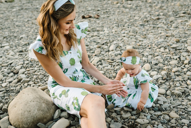 妈妈和女儿坐在湖边的沙滩上玩石头。暑假的概念。母亲的,宝宝的一天。花时间在一起。家人看。图片下载