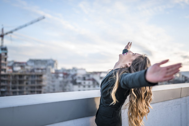 女商人在城市的屋顶上庆祝图片下载