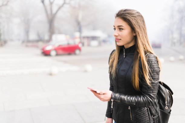 拿着电话等优步的可爱女人图片下载