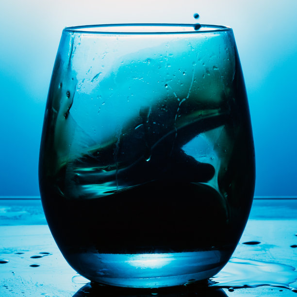 在蓝色纹理背景上洒上一杯葡萄酒。图片下载