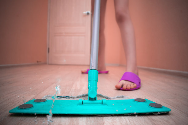 用拖把拖地的人。往地板上喷水。图片下载
