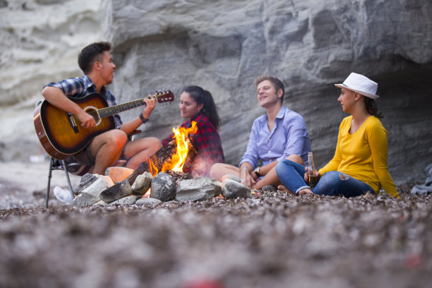 朋友们在沙滩上弹吉他，围着篝火唱歌图片下载
