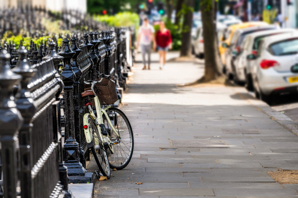 伦敦，英国肯辛顿的社区，有房子，阳台，阳台和自行车在栏杆上停放在夏天，人们走在人行道上图片下载