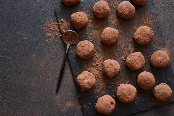 黑色背景下的石头板上的松露巧克力。从以上观点。图片下载