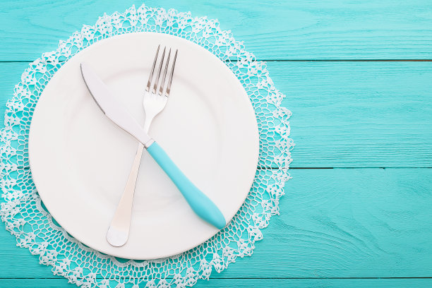 蓝色木质背景的蕾丝桌布上的婚礼餐具。俯视图和复制空间。有选择性的重点图片下载