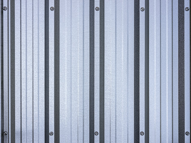 镀锌的锌金属屋顶板背景显示脊轮廓的纹理与紧固件螺栓在图像的顶部和底部框架的中心。图片下载