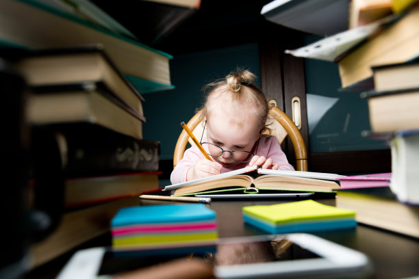 一个戴着大眼镜的孩子煞费苦心地在笔记本上写着什么素材图片