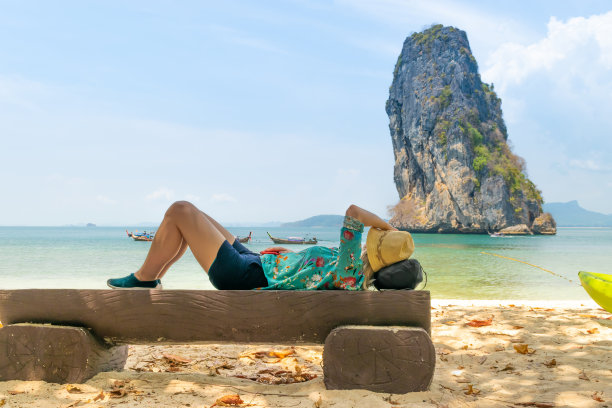 在泰国，一个金发女人躺在长凳上，看着大海图片下载