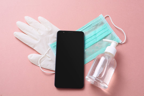 上面的平顶近距离查看照片的手机，医疗面罩，洗手液，手套隔离在粉红色的背景图片下载