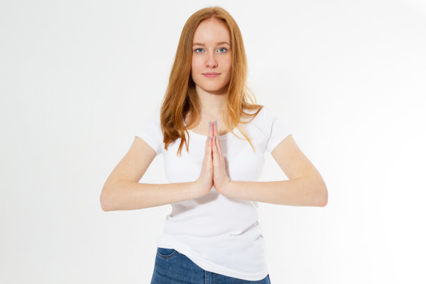 室内特写，美丽的红发女子穿着白色t恤，在灯光背景下练习瑜伽和冥想，双手合十手相握，看起来平静、放松和和平图片下载