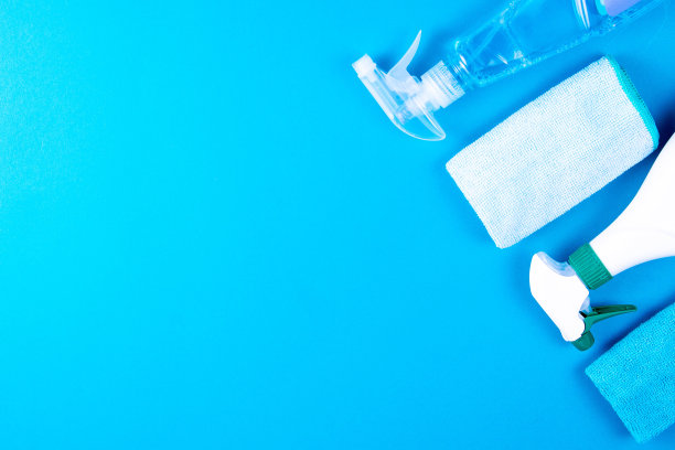 蓝色的手套，蓝色的抹布和洗涤剂站在蓝色的背景上。用于厨房、浴室和其他房间不同表面的清洁剂。顶部视野与清晰的空间图片下载
