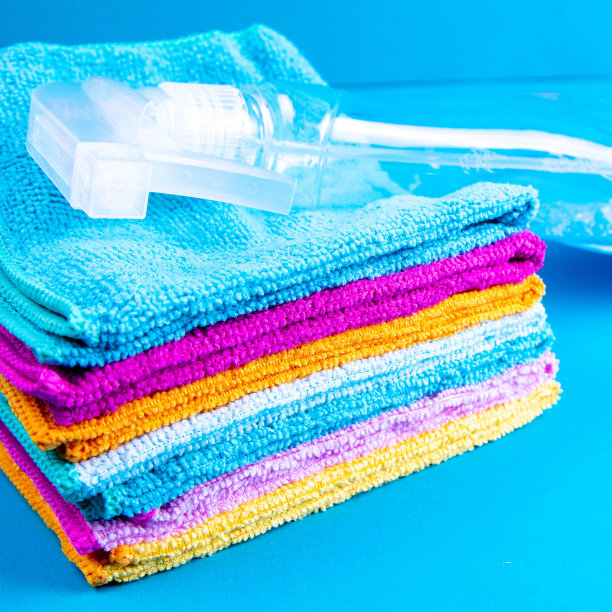 蓝色背景上放着干净的毛巾和五颜六色的毛巾。用于厨房、浴室和其他房间不同表面的清洁剂。特写镜头图片下载