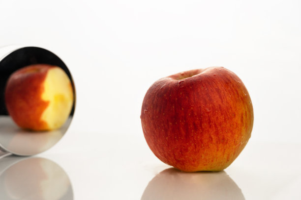 红橙苹果水果为食物在镜子中的悖论现实概念上的白色背景图片下载