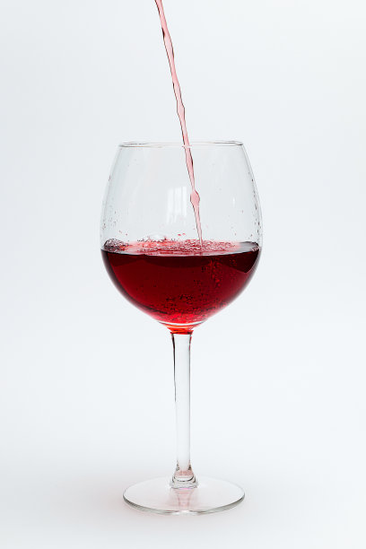 将红酒倒入一个白色背景的大玻璃杯中图片下载