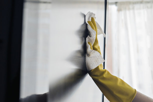 一个女人用湿布擦拭电视上的灰尘图片下载