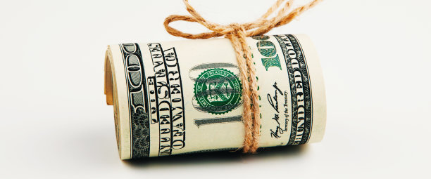 孤立的美元。一大卷百元钞票躺在白色的背景上图片下载