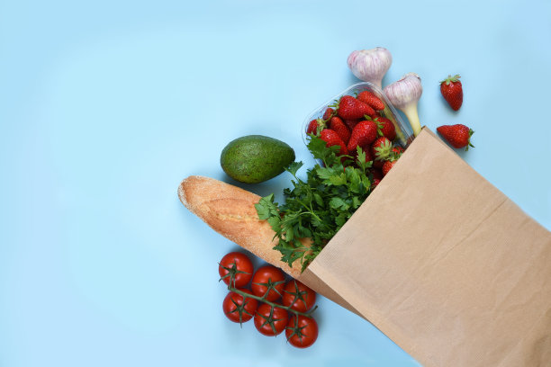 纸袋里装着不同的东西:草莓，西红柿，法棍面包，欧芹，鳄梨。购物食品外卖。图片下载