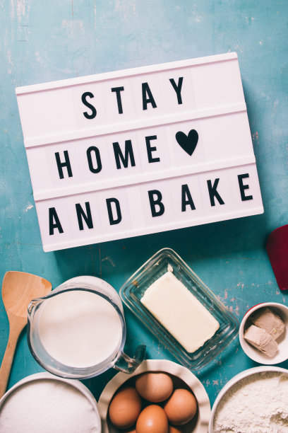 待在家里烤新冠病毒概念图像的冠状病毒大流行，与一个灯箱短信待在家里烤，圈上工具和配料烘焙面包和蛋糕在隔离期间，俯视图图片下载
