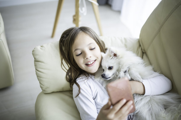 可爱的女孩躺在沙发上和她的狗在客厅在家里库存照片图片下载