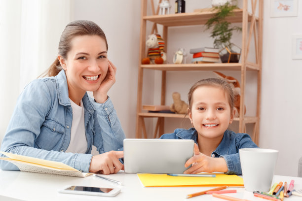 年轻的成年妇女和她的小女儿一起坐在桌子后面素材图片