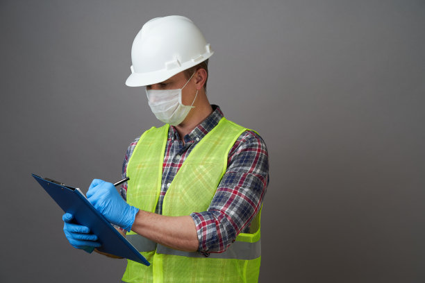 年轻的工程师戴着白色头盔和医用口罩。图片下载