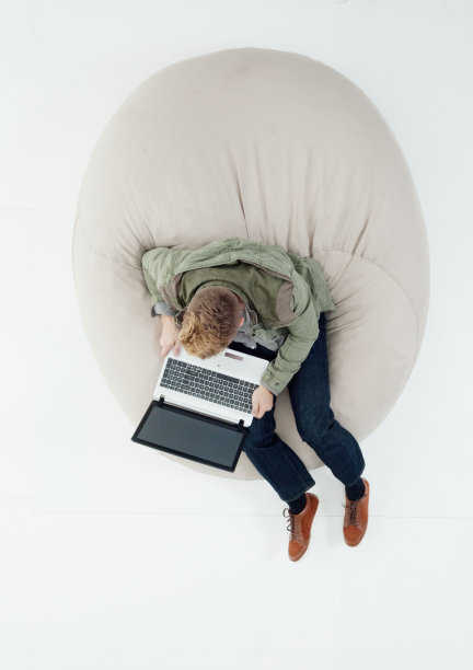 白人男孩穿着裤子在白色背景前休息，使用笔记本电脑图片下载