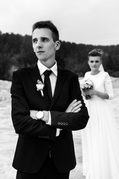 华丽的新娘和时尚的新郎手牵着手看着沙滩湖，黑白照片，豪华的婚礼图片下载
