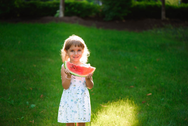 可爱的小女孩吃着西瓜，享受野餐图片下载