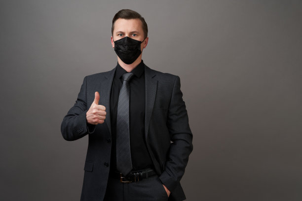 年轻商人戴着医用口罩，竖起大拇指图片下载