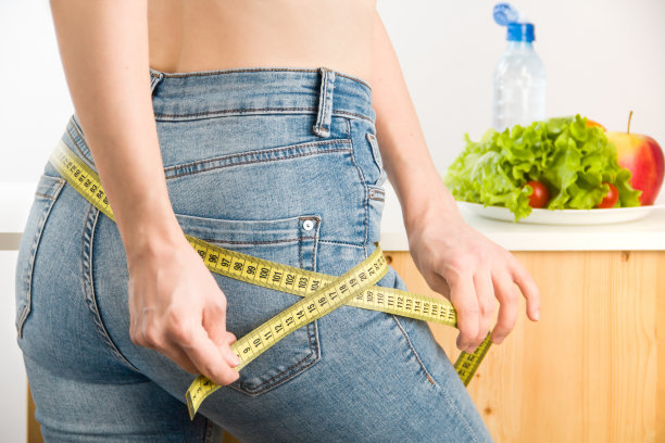 测量臀部的女人。饮食和健康的生活方式。紧身牛仔裤图片下载