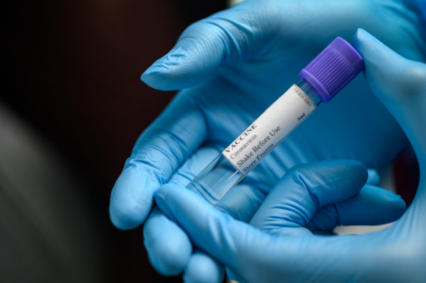手戴防护手套，将冠状病毒疫苗放在实验室试管中进行Covid-19检测图片下载