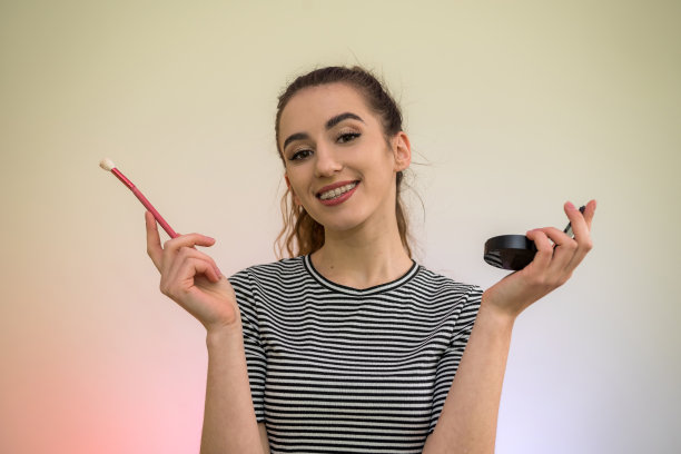 迷人的女孩与化妆刷隔离在绿色。美丽与健康的概念。图片下载