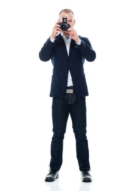 白人男性游客穿着牛仔裤，手持相机站在白色背景前图片下载