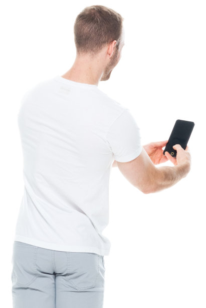 白人年轻男性穿着裤子站在白色背景前使用手机图片下载