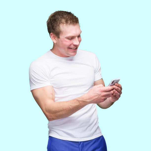 白人年轻男性穿着t恤站在有色背景前使用智能手机图片下载