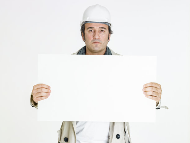 微笑的男建筑师在白色背景上举着空白横幅。图片下载