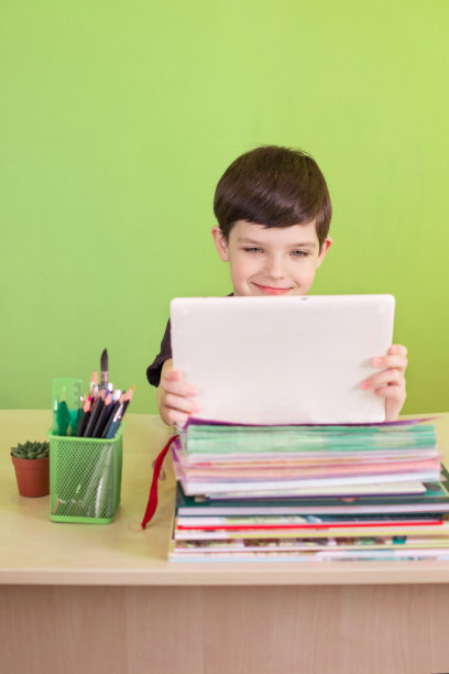 一名男孩在冠状病毒隔离期间一边做作业一边使用平板电脑。远程教育的概念。图片下载