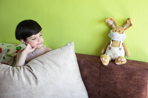 男孩在家里戴着复活节兔子面具，象征着2020年孤独的复活节。图片下载