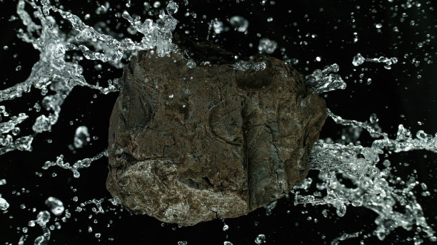 一块煤被水溅起。护肤护肤的美容理念。图片下载