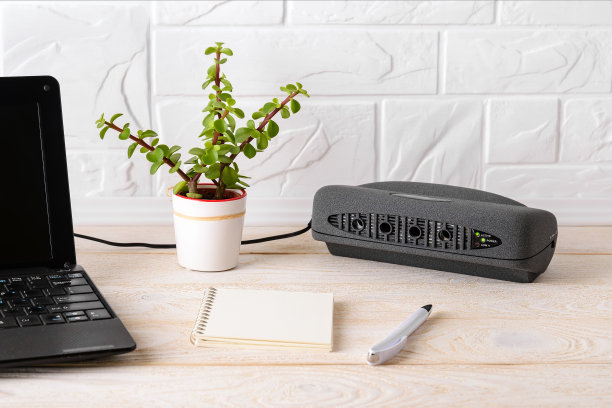 白色木桌上笔记本电脑旁边的黑色空气电离器。带有负离子发生器的空气净化器，可净化公寓或办公室内的空气及细微灰尘、异味。图片下载