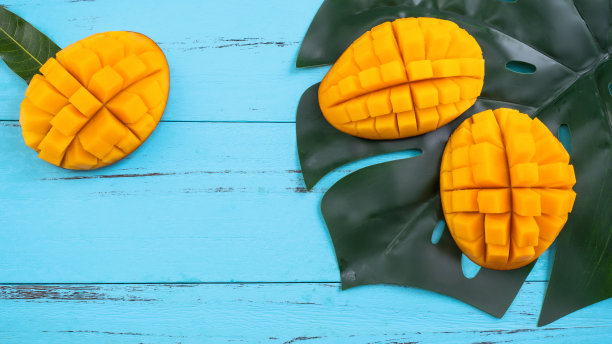 芒果-新鲜切碎的热带芒果水果孤立在明亮的充满活力的浅蓝色木制桌子背景，俯视图，平面布局，头顶拍摄。图片下载
